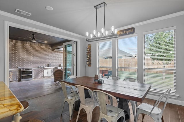 dining room featuring dark hardwood / wood-style flooring, ceiling fan with notable chandelier, ornamental molding, and brick wall