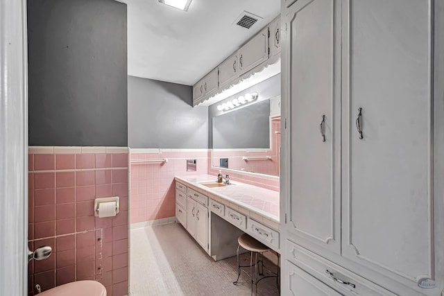 1510 W School St, Stanton, TX 79782 - bathroom featuring tile walls, vanity, toilet, tile patterned flooring, and wainscoting