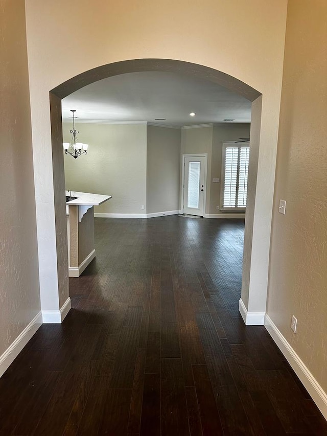 interior space featuring an inviting chandelier, dark wood finished floors, baseboards, and arched walkways
