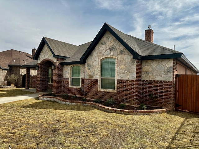 view of front facade featuring a chimney, stone siding, and brick siding
