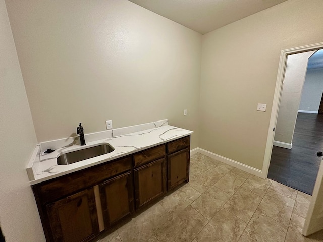 clothes washing area featuring baseboards and a sink