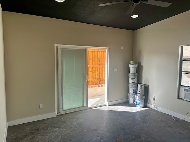empty room featuring cooling unit, baseboards, a ceiling fan, and concrete floors