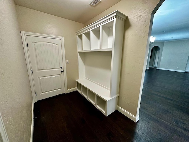 mudroom featuring arched walkways, dark wood-style flooring, visible vents, and a textured wall