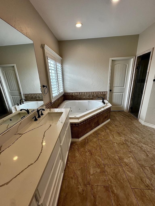 bathroom featuring a jetted tub, vanity, and recessed lighting