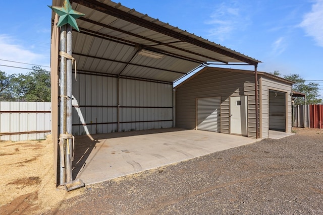 view of outbuilding featuring fence, an outbuilding, and a carport