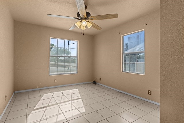 unfurnished room featuring ceiling fan, light tile patterned flooring, a textured ceiling, and baseboards