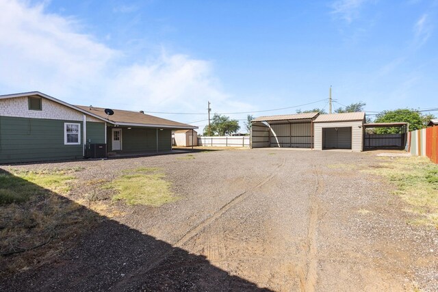 610 S Clay St, Midland, TX 79701 - view of yard with dirt driveway, a carport, fence, an outbuilding, and central AC