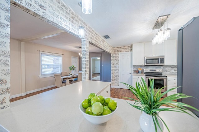 1207 Kansas, Midland, TX 79705 - kitchen featuring appliances with stainless steel finishes, ornate columns, white cabinetry, dark wood finished floors, and light countertops