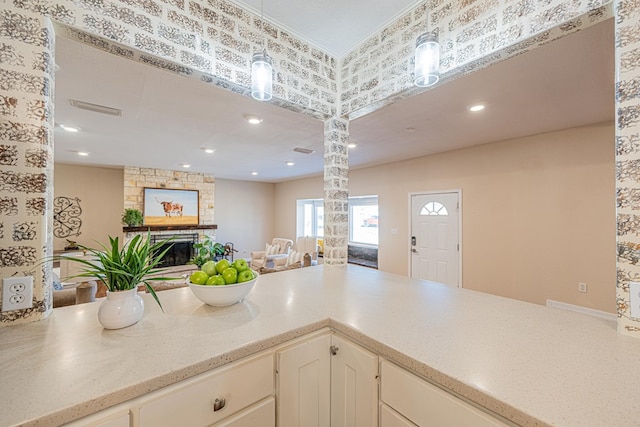 1207 Kansas, Midland, TX 79705 - kitchen with ornate columns, a fireplace, open floor plan, decorative light fixtures, and light stone counters