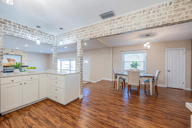 1207 Kansas, Midland, TX 79705 - kitchen with dark wood-type flooring, healthy amount of natural light, decorative columns, white cabinets, and a textured ceiling