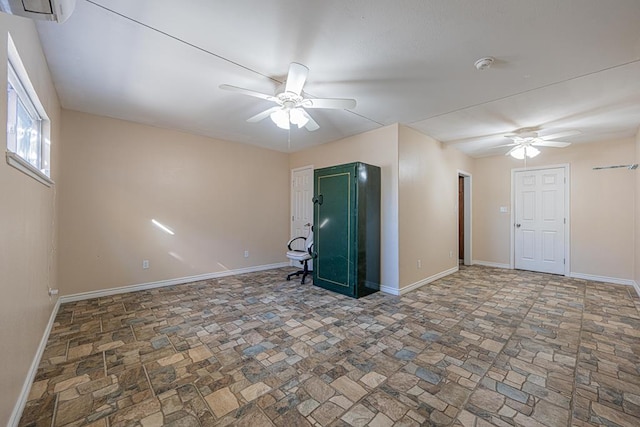 1207 Kansas, Midland, TX 79705 - empty room featuring a ceiling fan, stone tile floors, a wall unit AC, and a smoke detector