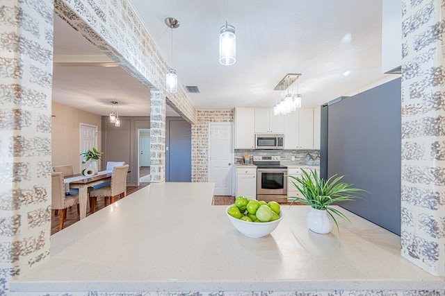 1207 Kansas, Midland, TX 79705 - kitchen with stainless steel appliances, white cabinets, hanging light fixtures, decorative backsplash, and a chandelier