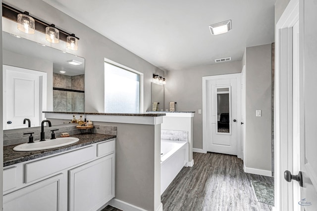 2408 Partridge St, Midland, TX 79705 - bathroom featuring vanity, a garden tub, wood finished floors, and an enclosed shower