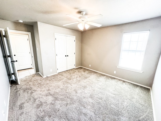 unfurnished bedroom with a ceiling fan, a textured ceiling, a closet, carpet flooring, and baseboards