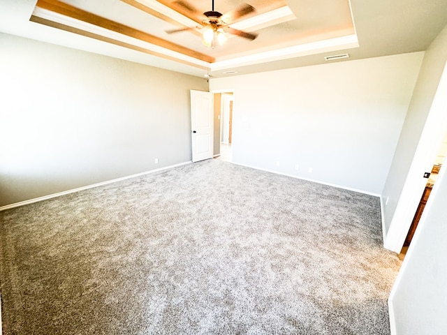 unfurnished bedroom featuring visible vents, carpet, and a tray ceiling