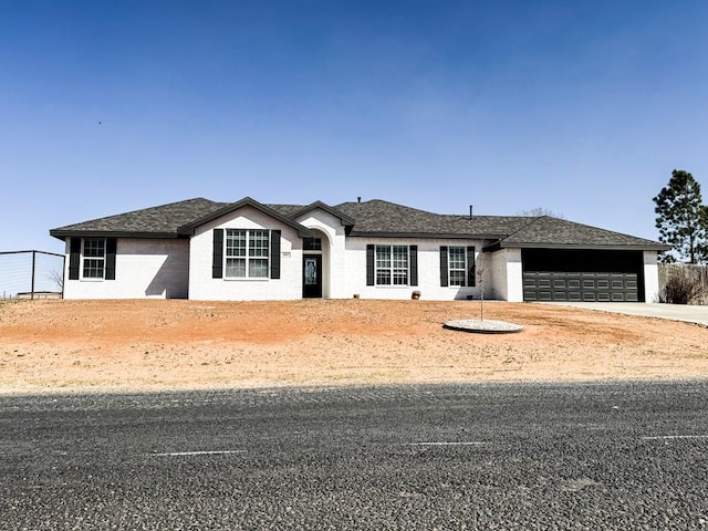 ranch-style home with a garage, fence, driveway, and a shingled roof