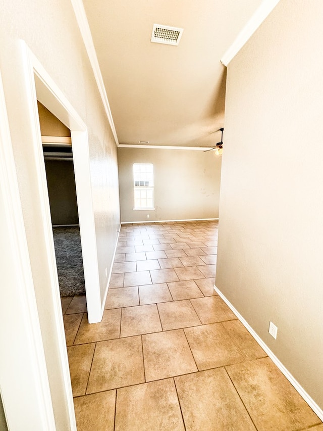 hall featuring crown molding, light tile patterned flooring, baseboards, and visible vents