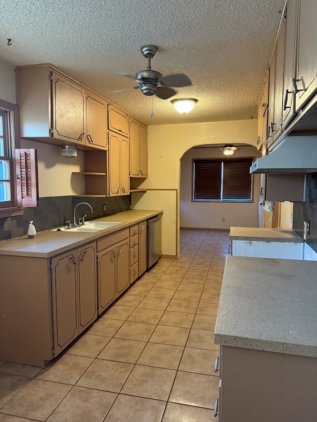 kitchen featuring kitchen peninsula, ceiling fan, light tile patterned flooring, stainless steel dishwasher, and sink