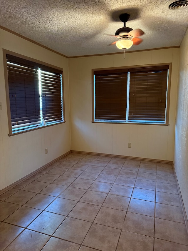 empty room featuring ceiling fan, light tile patterned floors, and crown molding