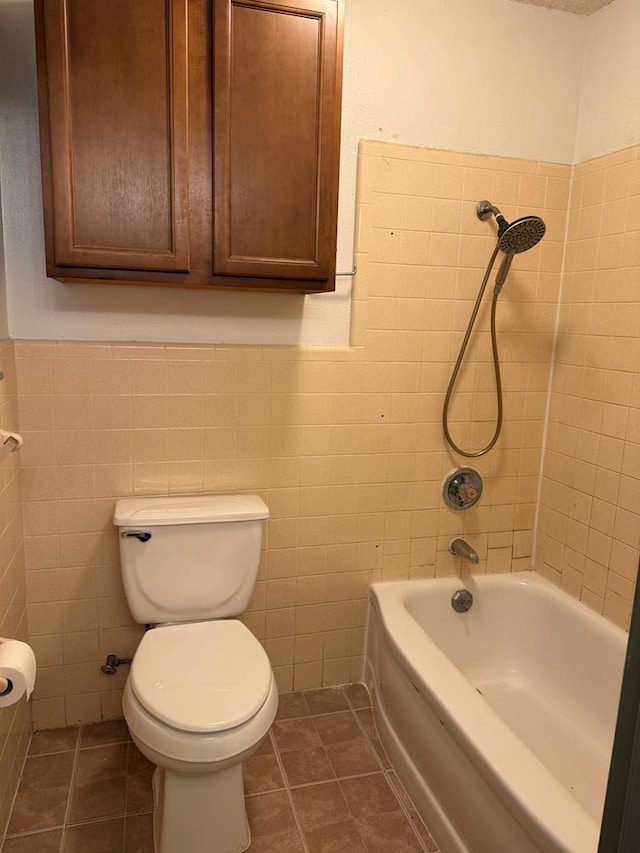 bathroom with toilet, tile patterned flooring, tile walls, and tiled shower / bath