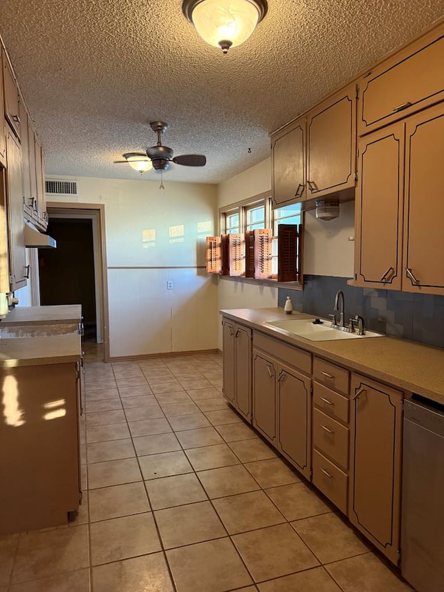 kitchen with light tile patterned floors, ceiling fan, dishwasher, a textured ceiling, and sink