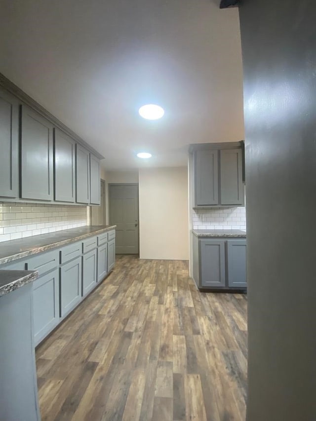 kitchen with decorative backsplash, dark hardwood / wood-style flooring, and gray cabinetry