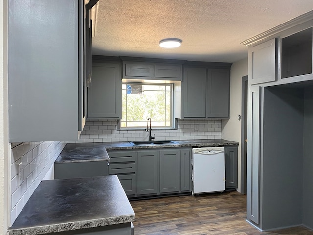 kitchen with dark hardwood / wood-style flooring, tasteful backsplash, gray cabinetry, sink, and dishwasher