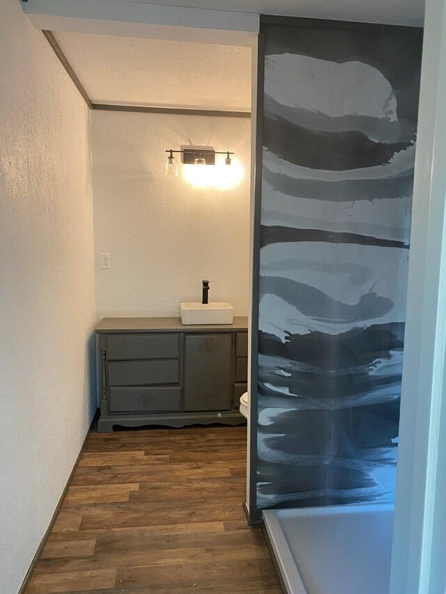 bathroom featuring toilet, sink, hardwood / wood-style floors, and ornamental molding