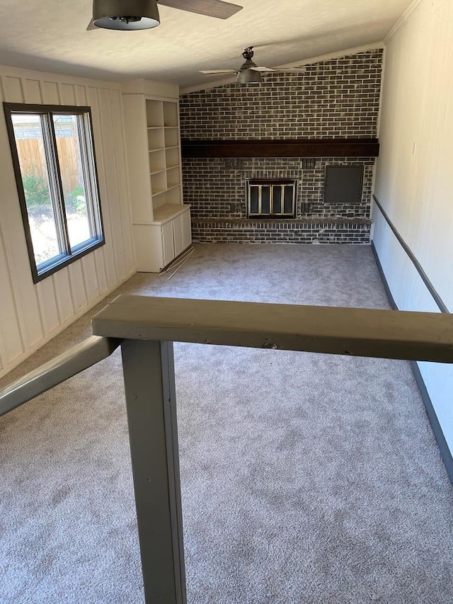 interior space featuring ceiling fan, built in features, carpet floors, and a brick fireplace