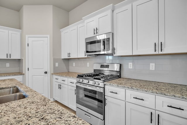 kitchen featuring backsplash, stainless steel appliances, and white cabinets