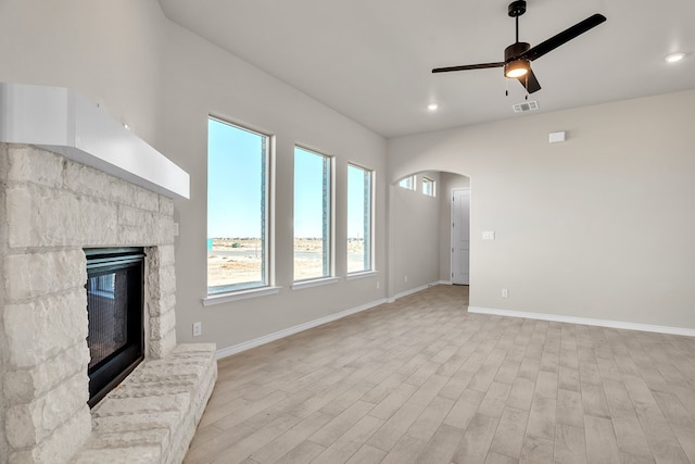 unfurnished living room featuring ceiling fan, a fireplace, and light wood-type flooring