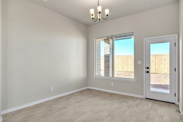 doorway featuring light wood-type flooring, a wealth of natural light, and a chandelier