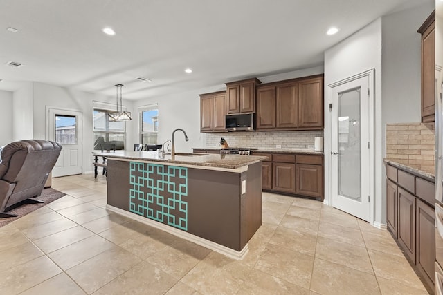kitchen with decorative backsplash, stainless steel microwave, open floor plan, and a sink