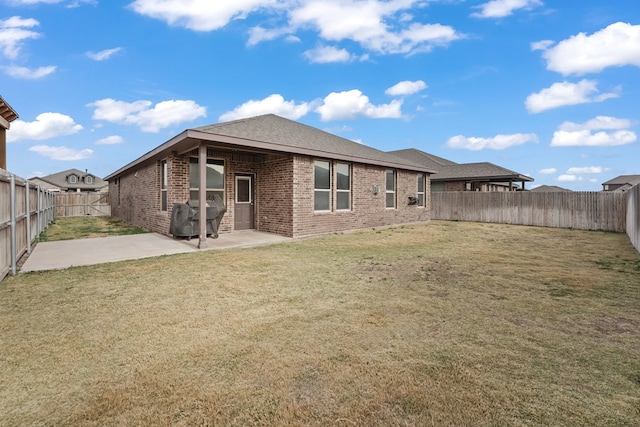 rear view of property with brick siding, a patio area, a lawn, and a fenced backyard