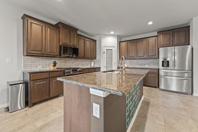 kitchen with stone counters, recessed lighting, decorative backsplash, stainless steel appliances, and a sink