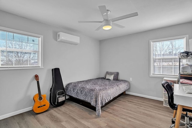 bedroom featuring ceiling fan, a wall mounted AC, and light hardwood / wood-style floors