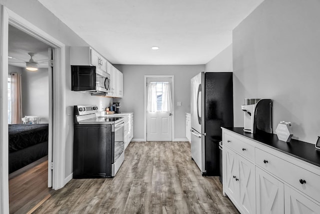 kitchen with stainless steel appliances, light hardwood / wood-style floors, and white cabinets