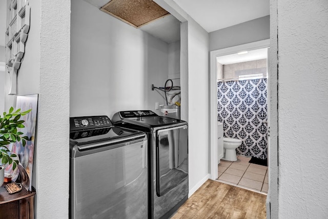 clothes washing area with washing machine and clothes dryer and light hardwood / wood-style floors