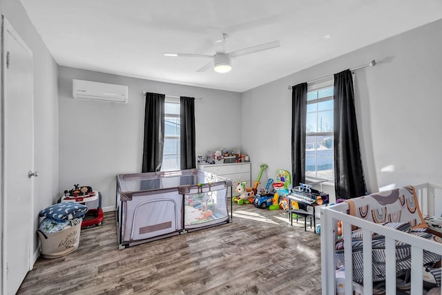 bedroom featuring multiple windows, an AC wall unit, hardwood / wood-style floors, and ceiling fan