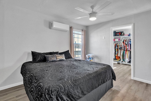 bedroom with hardwood / wood-style flooring, a walk in closet, a wall mounted air conditioner, and a closet