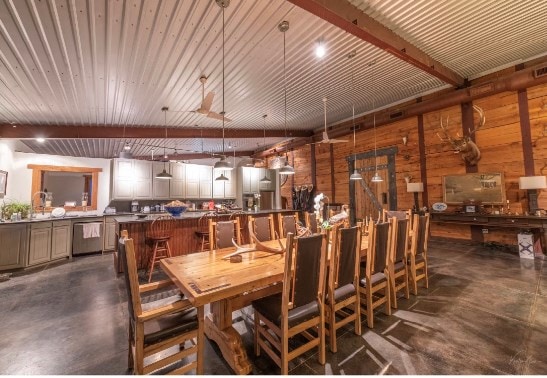 dining room with beamed ceiling and wood walls