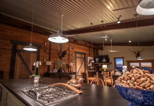 kitchen with wooden walls, ceiling fan, beam ceiling, and stainless steel gas cooktop