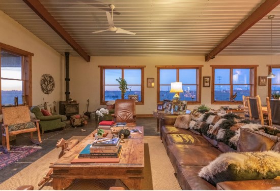 carpeted living room with beam ceiling, a wood stove, and ceiling fan