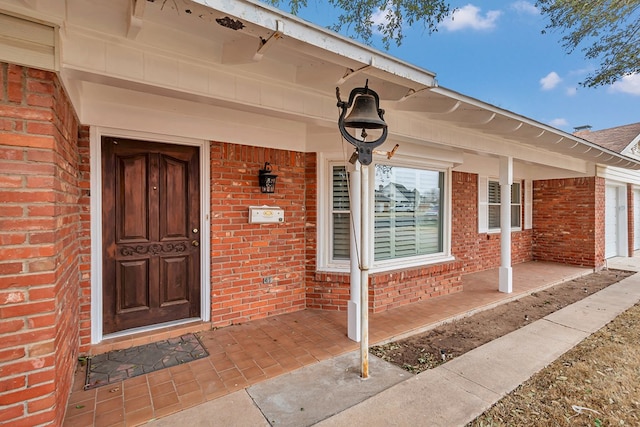 entrance to property with brick siding and a porch