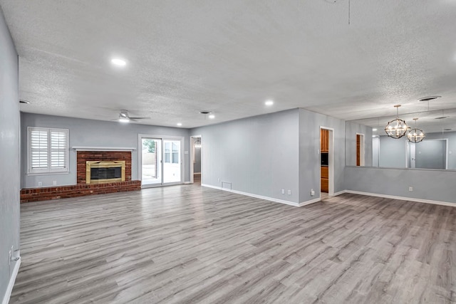 unfurnished living room featuring ceiling fan with notable chandelier, a textured ceiling, and wood finished floors