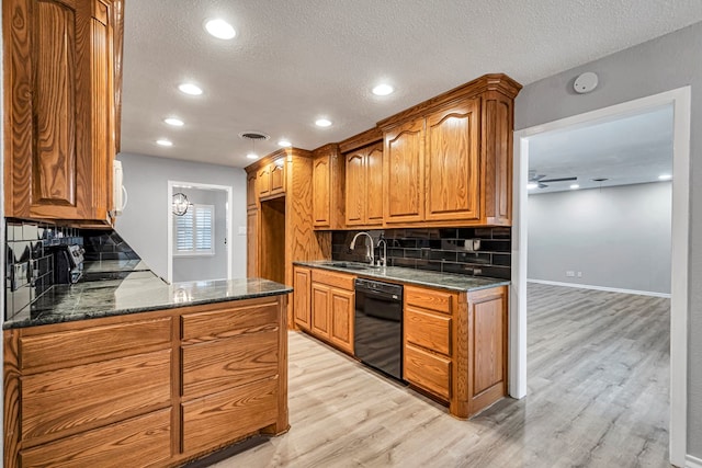 kitchen featuring dark stone countertops, a sink, light wood-style floors, dishwasher, and brown cabinets