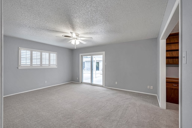 carpeted empty room with a ceiling fan, baseboards, and a textured ceiling