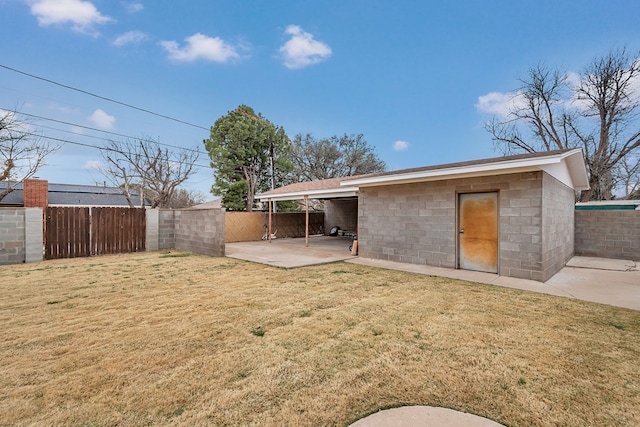 rear view of property featuring a lawn, concrete block siding, and fence