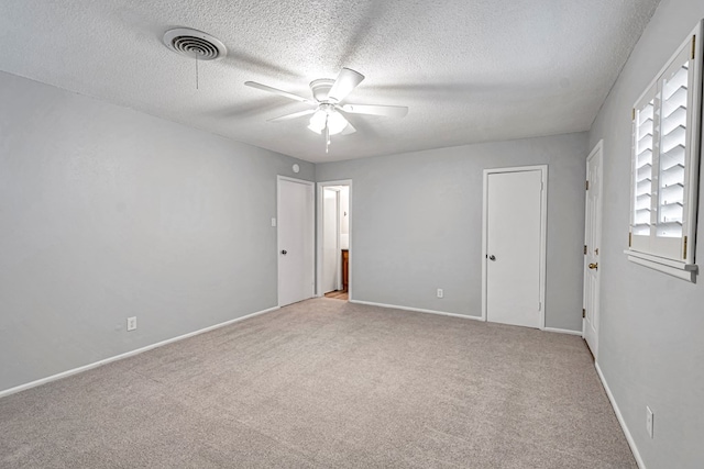 unfurnished room featuring visible vents, baseboards, carpet flooring, a textured ceiling, and a ceiling fan