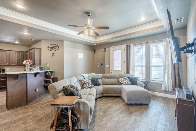 6108 Copper Sky Ct, Midland, TX 79705 - living area featuring a tray ceiling, crown molding, light wood-type flooring, a ceiling fan, and baseboards